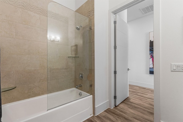 bathroom with hardwood / wood-style flooring and tiled shower / bath