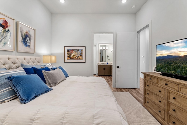 bedroom with ensuite bath and light hardwood / wood-style floors