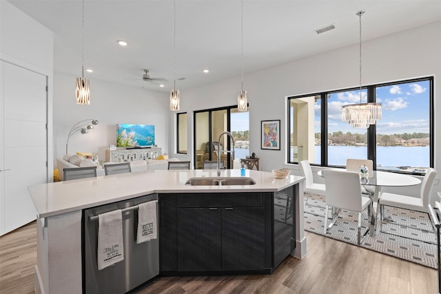 kitchen with stainless steel dishwasher, a kitchen island with sink, sink, and hanging light fixtures