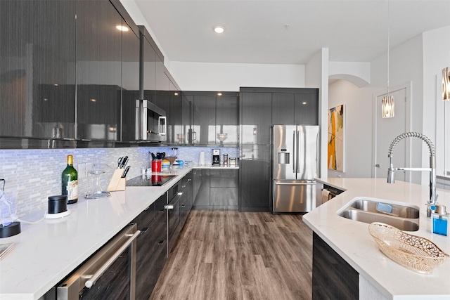 kitchen with appliances with stainless steel finishes, wood-type flooring, sink, wine cooler, and hanging light fixtures