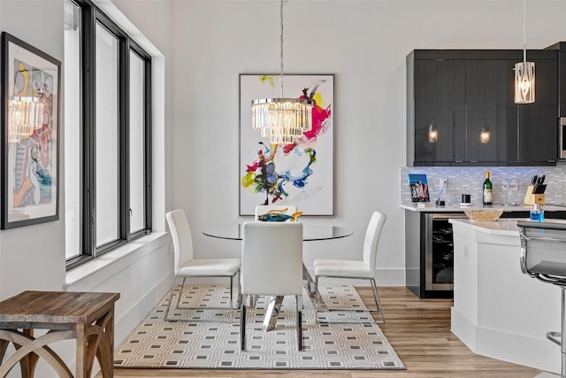 dining space with wine cooler, a notable chandelier, a healthy amount of sunlight, and light wood-type flooring