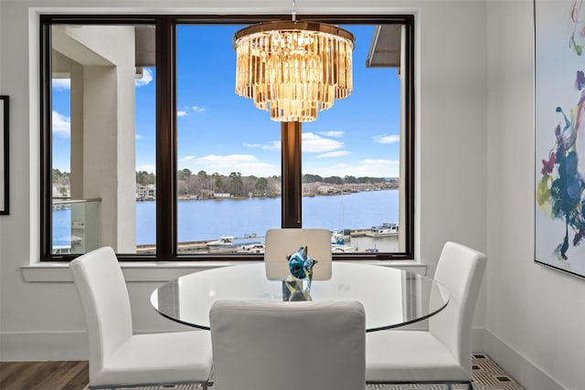 dining room with hardwood / wood-style flooring, a water view, and a chandelier