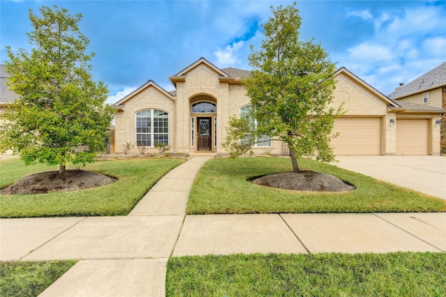 view of front facade with a garage, a front yard, concrete driveway, and brick siding