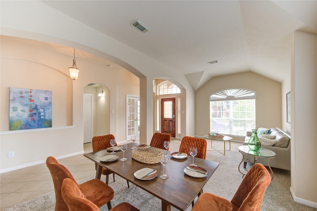 dining space featuring arched walkways, vaulted ceiling, light tile patterned flooring, and visible vents