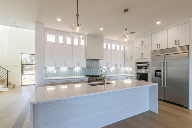 kitchen featuring appliances with stainless steel finishes, sink, white cabinets, and decorative light fixtures