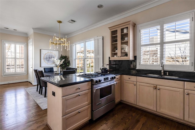 kitchen featuring sink, stainless steel gas range oven, decorative light fixtures, ornamental molding, and kitchen peninsula