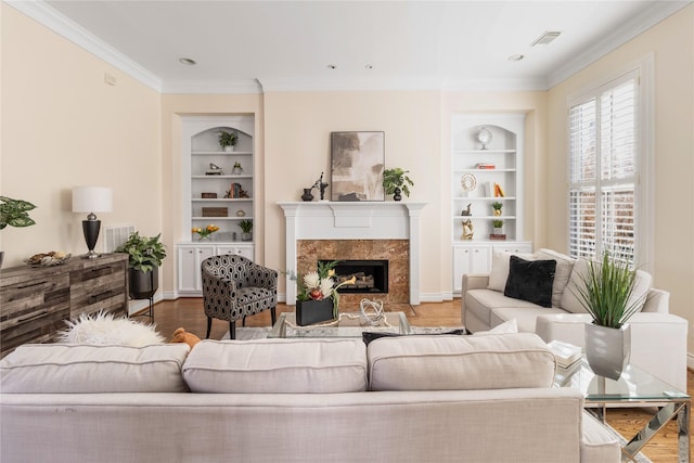 living room with built in shelves, a high end fireplace, crown molding, and hardwood / wood-style floors