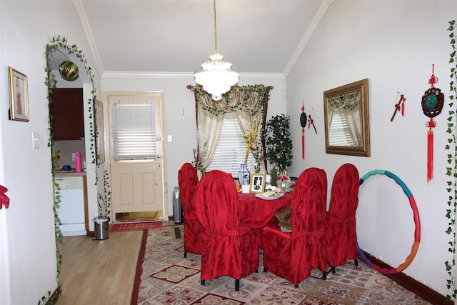 dining room featuring crown molding, vaulted ceiling, light wood-type flooring, and a notable chandelier