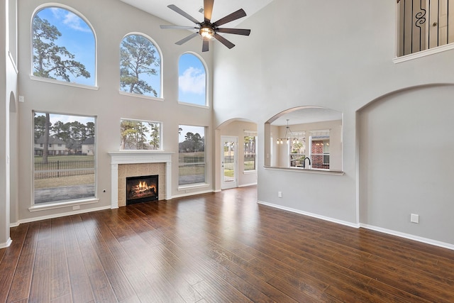 unfurnished living room with a tile fireplace, dark wood finished floors, baseboards, and ceiling fan