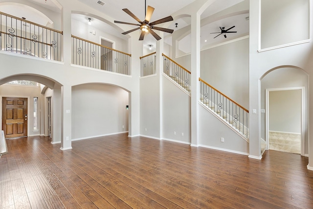 unfurnished living room featuring dark hardwood / wood-style floors, ceiling fan, and a high ceiling