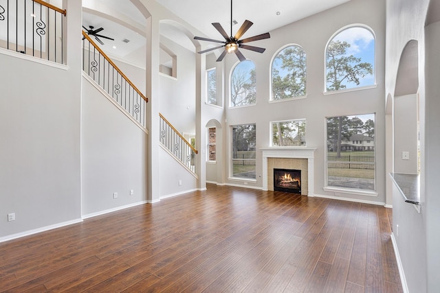 unfurnished living room featuring ceiling fan, a fireplace, and dark hardwood / wood-style flooring