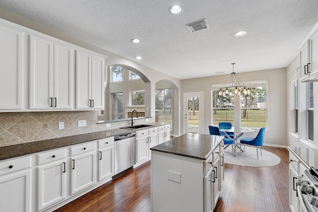 kitchen with sink, dishwasher, white cabinetry, dark hardwood / wood-style floors, and a kitchen island