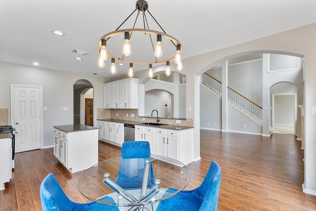 kitchen featuring stainless steel appliances, a sink, visible vents, a center island, and dark countertops