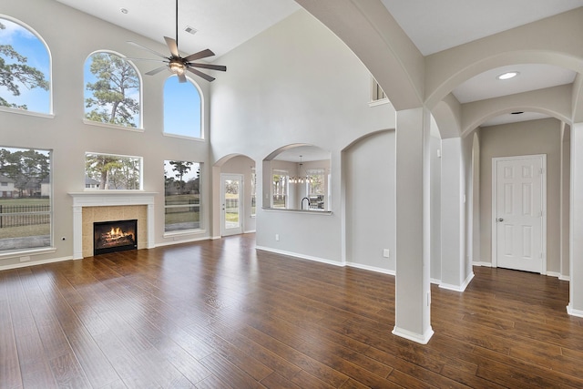 unfurnished living room with a fireplace, dark wood-type flooring, and ceiling fan