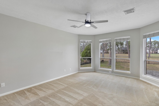 unfurnished room with light carpet, a ceiling fan, visible vents, and baseboards