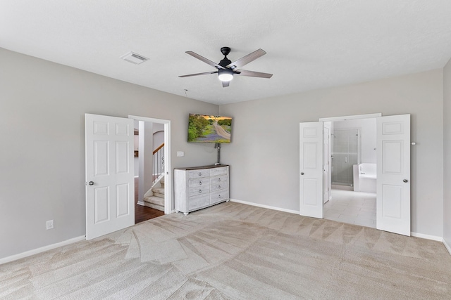 unfurnished bedroom featuring ceiling fan, light colored carpet, and connected bathroom