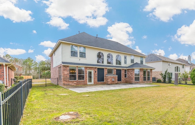 rear view of house with a fenced backyard, brick siding, roof with shingles, a lawn, and a patio area