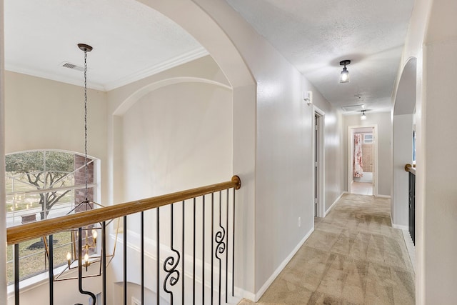 corridor featuring crown molding, light colored carpet, a chandelier, and a textured ceiling