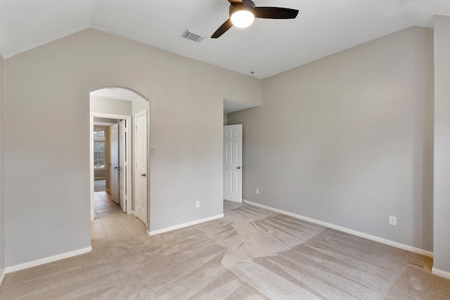 unfurnished room with lofted ceiling, arched walkways, visible vents, and light colored carpet