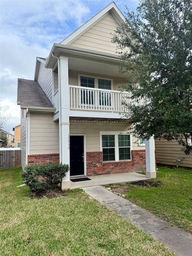 view of front of house featuring a balcony and a front lawn