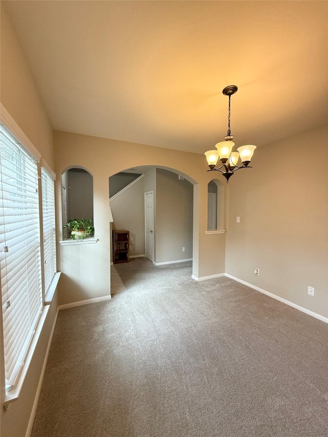 spare room with a chandelier and carpet flooring