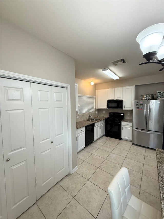 kitchen featuring white cabinetry, sink, light tile patterned floors, and black appliances