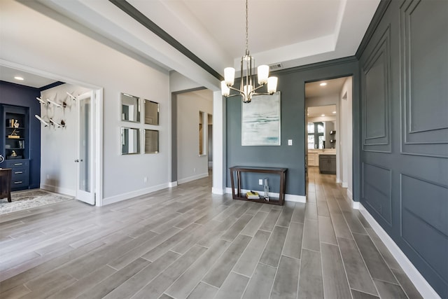 unfurnished dining area featuring a raised ceiling and a notable chandelier