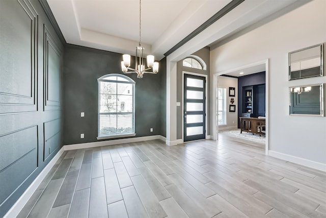 interior space featuring an inviting chandelier, a raised ceiling, and light hardwood / wood-style flooring