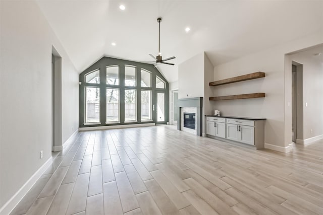 unfurnished living room featuring light hardwood / wood-style flooring, ceiling fan, and vaulted ceiling