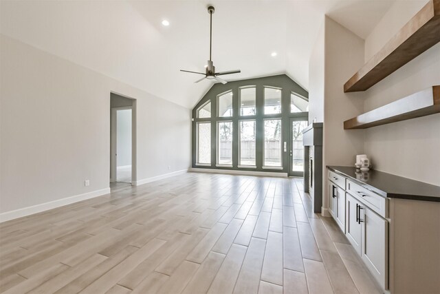 unfurnished living room with ceiling fan, lofted ceiling, and light hardwood / wood-style floors