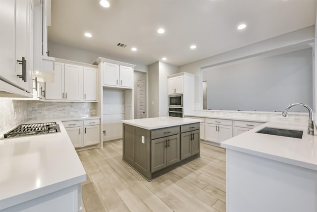 kitchen with gray cabinetry, a center island, sink, and white cabinets