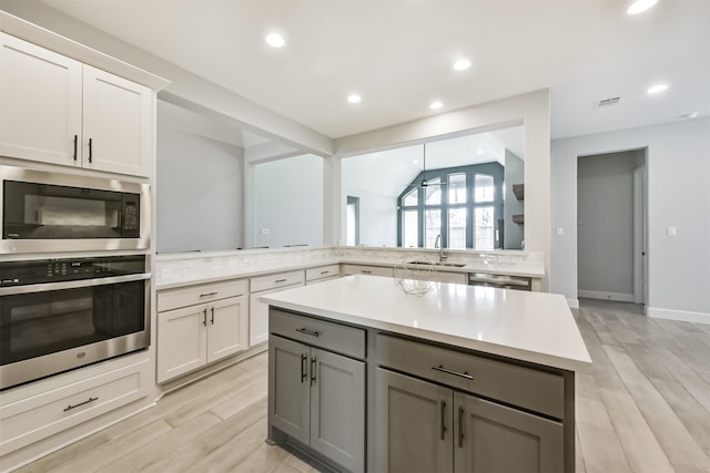 kitchen with stainless steel appliances, sink, gray cabinetry, and white cabinets