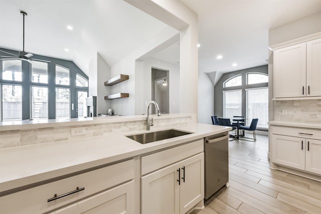 kitchen with lofted ceiling, sink, dishwasher, white cabinetry, and tasteful backsplash