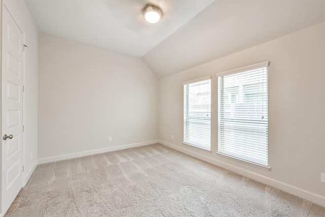 empty room with ceiling fan, light colored carpet, and vaulted ceiling