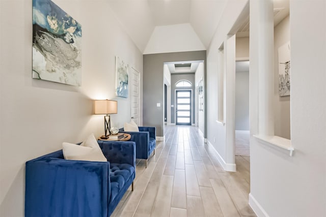 hallway featuring lofted ceiling and light hardwood / wood-style flooring