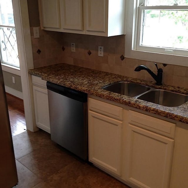 kitchen featuring tasteful backsplash, white cabinetry, dishwasher, sink, and dark stone counters