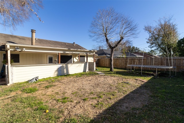 view of yard with a trampoline and fence