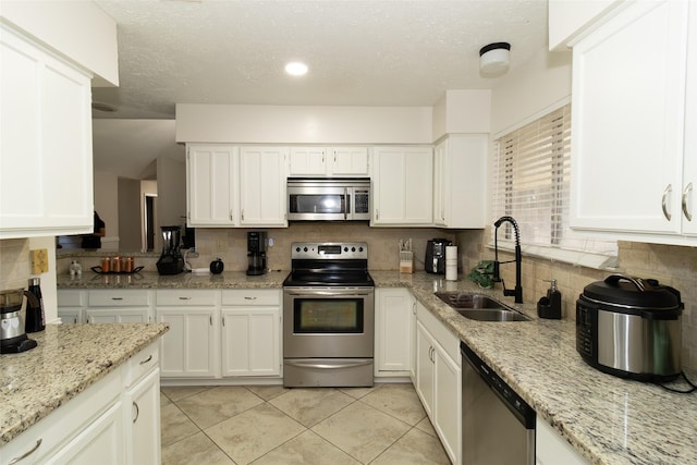 kitchen featuring tasteful backsplash, appliances with stainless steel finishes, white cabinetry, and a sink