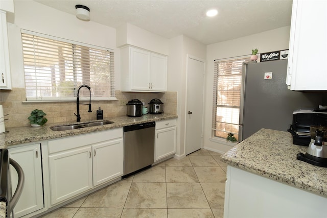 kitchen with a sink, stainless steel appliances, white cabinets, and decorative backsplash