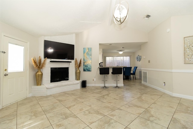 tiled living room featuring lofted ceiling, a healthy amount of sunlight, and a brick fireplace