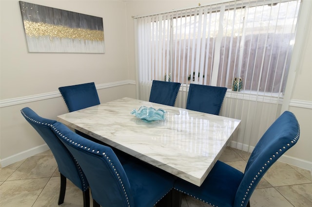 tiled dining space featuring baseboards