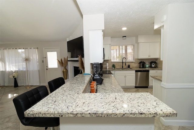 kitchen featuring a breakfast bar, sink, white cabinetry, kitchen peninsula, and dishwasher