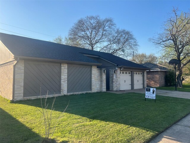 exterior space with a lawn, concrete driveway, brick siding, and a shingled roof