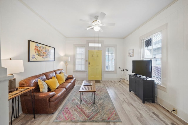 living room featuring crown molding, light hardwood / wood-style flooring, and a wealth of natural light