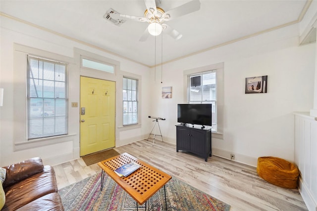 living room featuring crown molding, a wealth of natural light, and light hardwood / wood-style floors