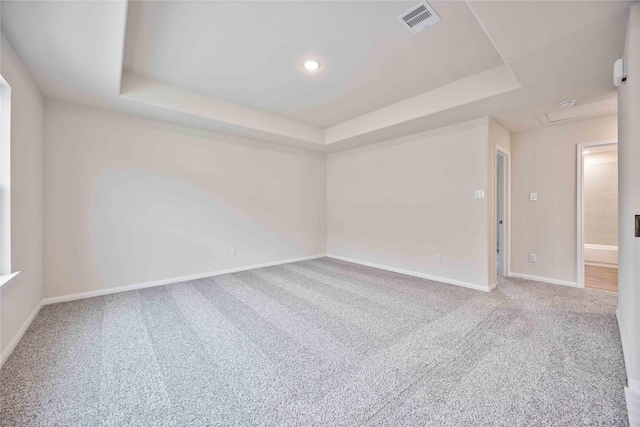 carpeted spare room with a tray ceiling