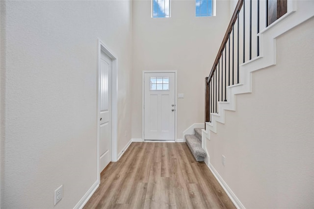 foyer with plenty of natural light, light hardwood / wood-style floors, and a high ceiling