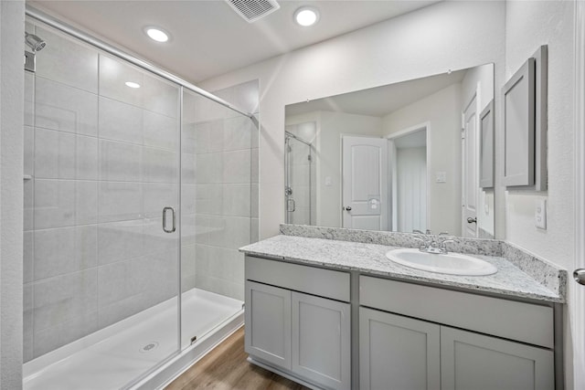 bathroom with walk in shower, vanity, and wood-type flooring