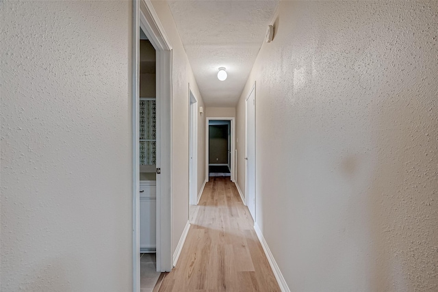 hallway featuring light hardwood / wood-style floors and a textured ceiling