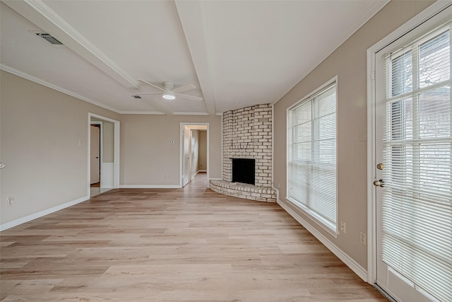 unfurnished living room featuring ceiling fan, a healthy amount of sunlight, a brick fireplace, and light wood-type flooring